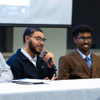 four college student panelists sitting at the front of the students at the front of the conference room